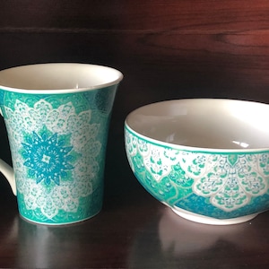 May include: A white ceramic mug and bowl with a teal and white mandala design.