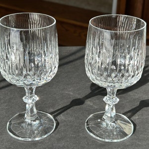 Puede incluir: Dos copas de vino de vidrio transparente con un dise&ntilde;o de vidrio cortado. Las copas tienen una copa redonda y un tallo alto con una base ancha.