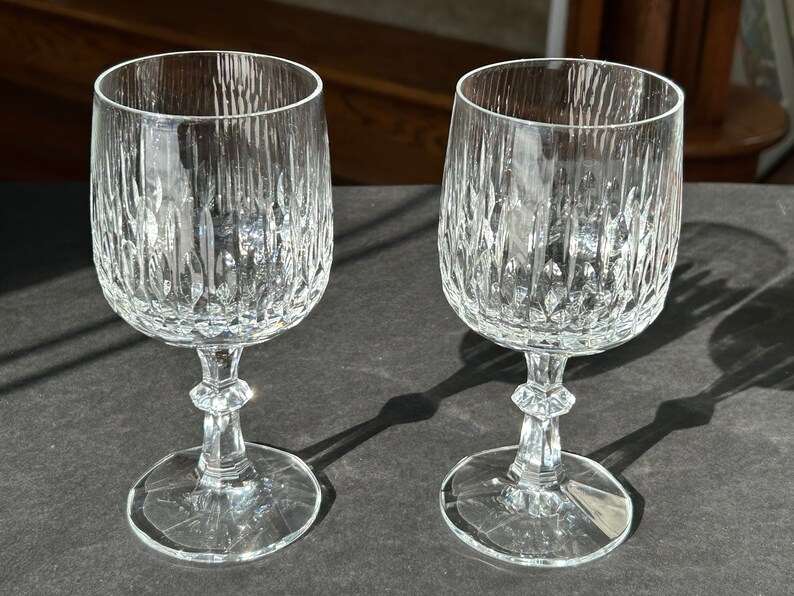 Puede incluir: Dos copas de vino de vidrio transparente con un dise&ntilde;o de vidrio cortado. Las copas tienen una copa redonda y un tallo alto con una base ancha.