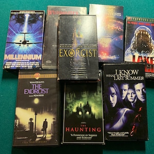 May include: A collection of VHS tapes featuring horror movies, including "The Exorcist", "I Know What You Did Last Summer", "The Haunting", and "Millennium".