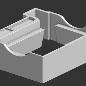 Puede incluir: Un contenedor de plástico gris claro, renderizado en 3D, con una base rectangular abierta y un compartimento adjunto. El compartimento tiene un diseño escalonado con un pequeño recorte rectangular. El contenedor tiene bordes redondeados.
