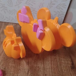 May include: Orange and pink plastic toy shaped like a cartoon character with large ears. The toy is in two pieces, one of which is a separate head.