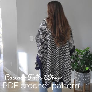 May include: A black and white houndstooth crochet wrap with a navy blue border. The wrap is worn over the shoulders. The text "Cascade Falls Wrap PDF crochet pattern" is at the bottom of the image.