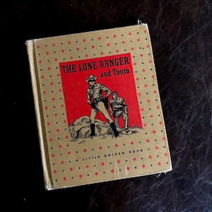 May include: A vintage "The Lone Ranger and Tonto" Little Golden Book. The cover features a red rectangle with illustrations of the Lone Ranger and Tonto. The book has a tan cover with red star accents.