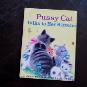 May include: A vintage children's book, "Pussy Cat Talks to Her Kittens," with a yellow cover. The illustration shows several kittens with blue and pink bows. The book is a Rand McNally Junior Elf Book.