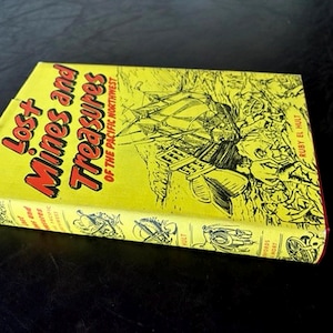 May include: A vintage book titled "Lost Mines and Treasures of the Pacific Northwest" with a yellow cover and black illustrations. The book's title is in red and black lettering. The author's name, Ruby El Hult, is visible.