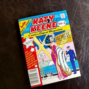 May include: A Katy Keene No. 1 Comics Digest Magazine featuring a colorful cover illustration of a woman in a magenta gown with a white fur stole standing next to a blue car and a person in a blue uniform. The cover includes text and a barcode.
