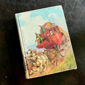 Pode incluir: Livro infantil vintage intitulado "The Alice and Jerry Books", com uma ilustração colorida de uma diligência puxada por cavalos. A capa mostra uma diligência vermelha com passageiros, bagagem e cavalos contra um céu azul.