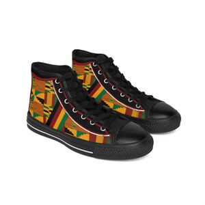 Puede incluir: Zapatillas de lona negras de caña alta con un patrón geométrico colorido en tonos amarillos, rojos y verdes. El patrón recuerda a los textiles africanos tradicionales.