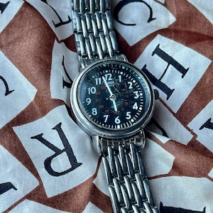 retro vintage silver Timex watch with a round circle case and black dial, white and red accents