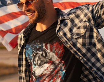 May include: A man wearing a black t-shirt with a wolf graphic and an American flag design. He is also wearing a blue and white plaid shirt and sunglasses. The man is standing in front of an American flag.