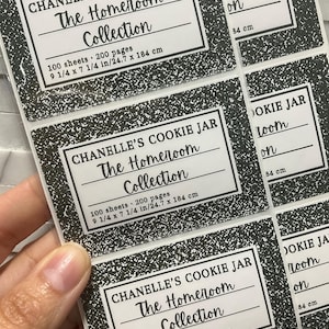 May include: A sheet of rectangular stickers featuring a black and white speckled composition notebook pattern. Each sticker displays the text CHANELLE'S COOKIE JAR, The Homeroom Collection, 100 sheets, 200 pages, and 9 1/4 x 7 1/4 in/24.7 x 184 cm.