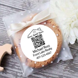 May include: A white round sticker with a black house icon, a QR code, and the text "Home Sweet Home", "Michael Ross", "Front Lake Realty", and "407-123-4567".