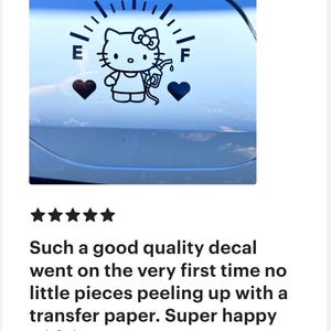 May include: A black vinyl decal applied to a smooth surface, featuring a fuel gauge graphic with the letters E and F. The design includes a cartoon cat character holding a gas pump nozzle, flanked by two solid black heart shapes on either side.