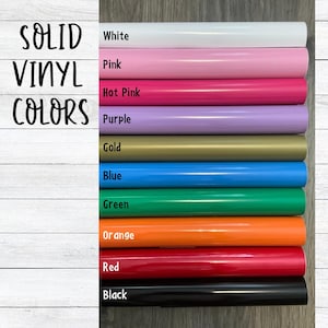May include: A collection of ten rolls of solid vinyl in various colors, stacked vertically. The colors are labeled as White, Pink, Hot Pink, Purple, Gold, Blue, Green, Orange, Red, and Black. The text "SOLID VINYL COLORS" is printed on the left side.
