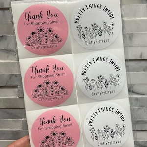 May include: A sheet of six circular stickers in a clear plastic sleeve. Three pink stickers feature black floral line art with the text Thank You For Shopping Small and Craftybyizzyus. Three white stickers feature black floral art with the text PRETTY THINGS INSIDE and Craftybyizzyus.