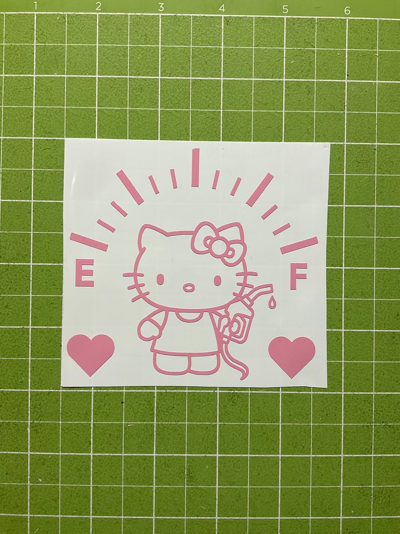 May include: A light pink vinyl decal featuring a cartoon cat character holding a fuel pump nozzle. The design includes a fuel gauge arc with the letters E and F, and two solid hearts on either side, all set against a white backing sheet.
