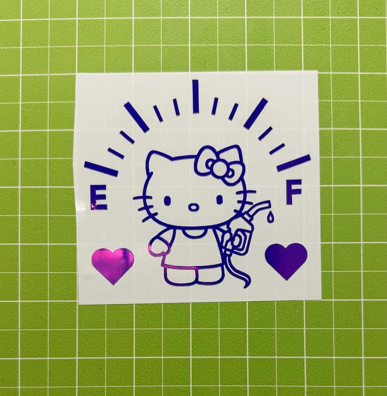May include: A purple vinyl decal featuring a Hello Kitty character holding a gas pump nozzle, positioned below a fuel gauge arc with the letters E and F on either side, flanked by two solid purple hearts on a white backing sheet.