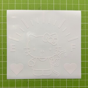 May include: A white vinyl decal featuring a line art illustration of a cat character with a bow, holding a gas pump nozzle. The design includes a fuel gauge arc with the letters E and F, and two heart shapes positioned at the bottom corners.