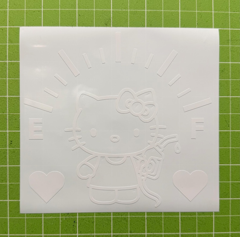 May include: A white vinyl decal featuring a line art illustration of a cat character with a bow, holding a gas pump nozzle. The design includes a fuel gauge arc with the letters E and F, and two heart shapes positioned at the bottom corners.