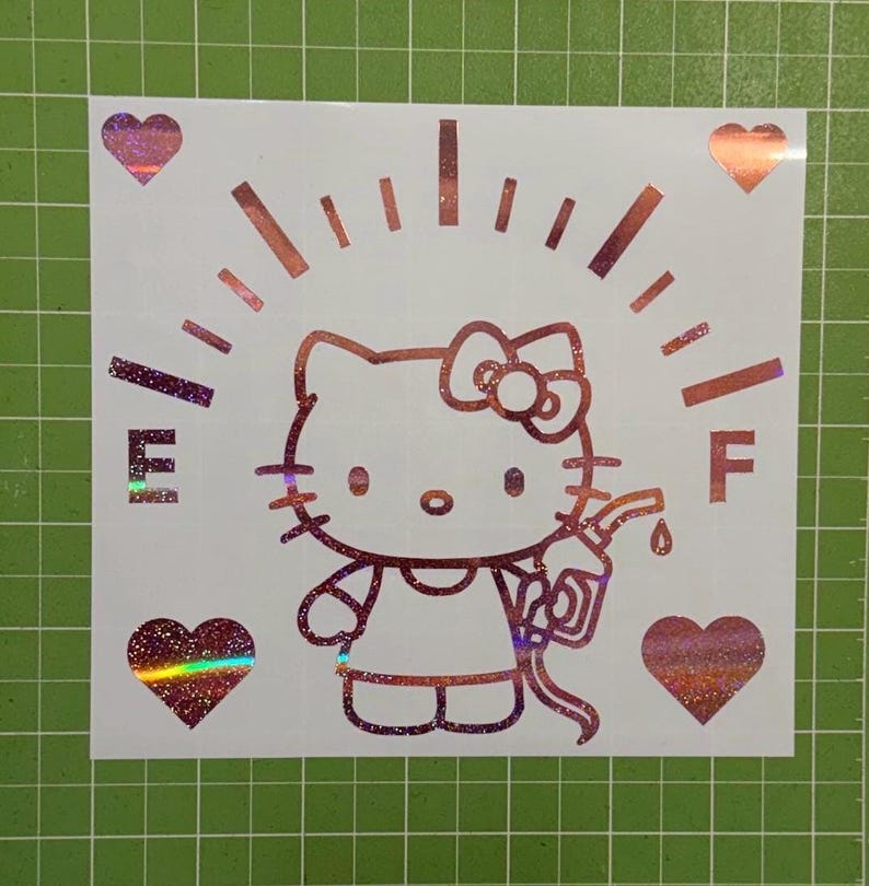May include: A holographic vinyl decal featuring a Hello Kitty character holding a gas pump nozzle. The design includes a fuel gauge arc with the letters E and F, and four hearts positioned in the corners, all rendered in a shimmering iridescent finish.