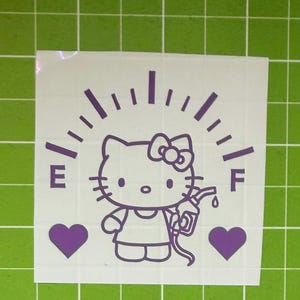 May include: A purple vinyl decal featuring a cartoon cat character with a bow, positioned below a fuel gauge arc with the letters E and F. The character holds a gas pump nozzle, flanked by two solid purple hearts on a white backing sheet.