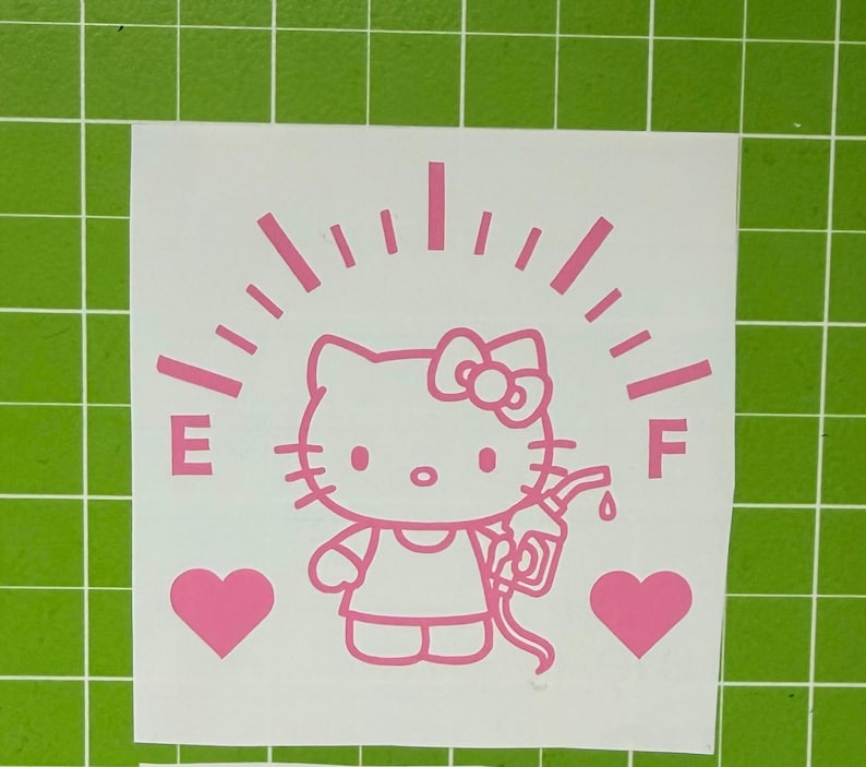 May include: A light pink vinyl decal featuring a cartoon cat character holding a fuel pump nozzle. The design includes a fuel gauge arc with the letters E and F, and two solid hearts on either side, all presented on a white backing sheet.