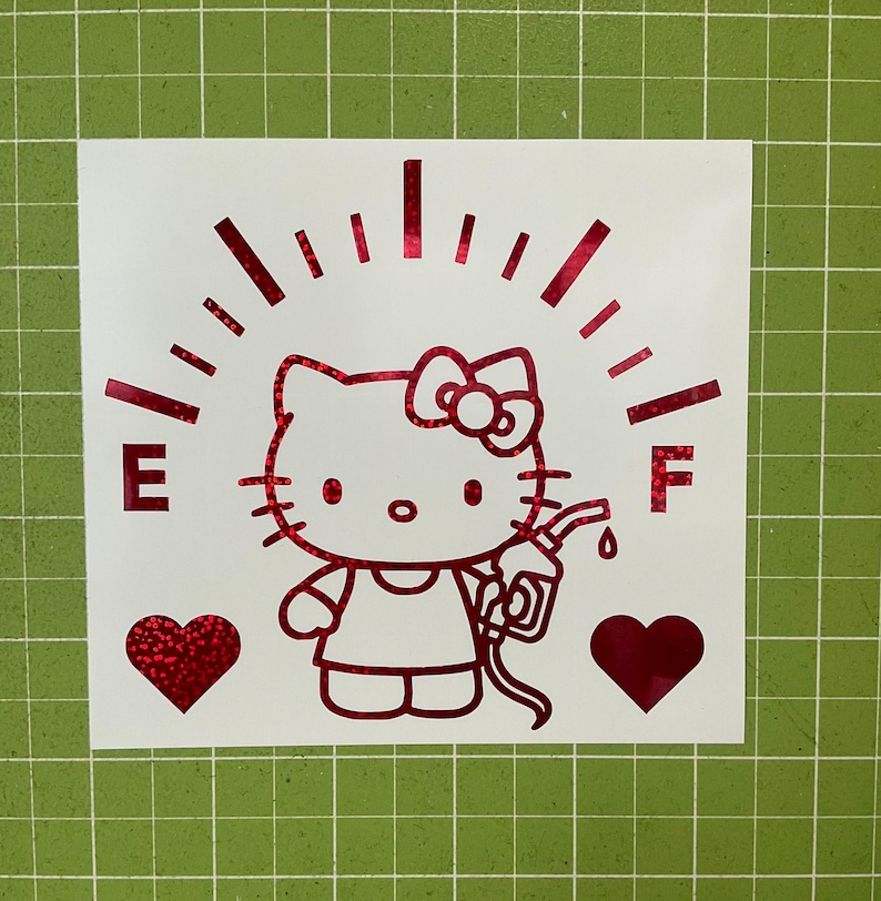 May include: A red holographic vinyl decal featuring a cartoon cat character holding a fuel pump nozzle. The design includes a fuel gauge arc with the letters E and F on either side, and two solid red hearts positioned below the character.