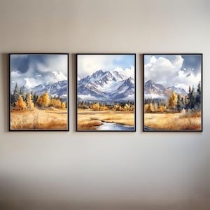 May include: A triptych of framed watercolour landscape paintings. Each depicts a mountain range with snow-covered peaks, a golden meadow, and trees in yellow and green hues. The sky is a blend of blue and grey.