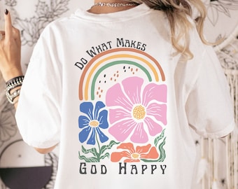 May include: White t-shirt with a rainbow and flowers graphic. The text "Do What Makes God Happy" is printed on the shirt.