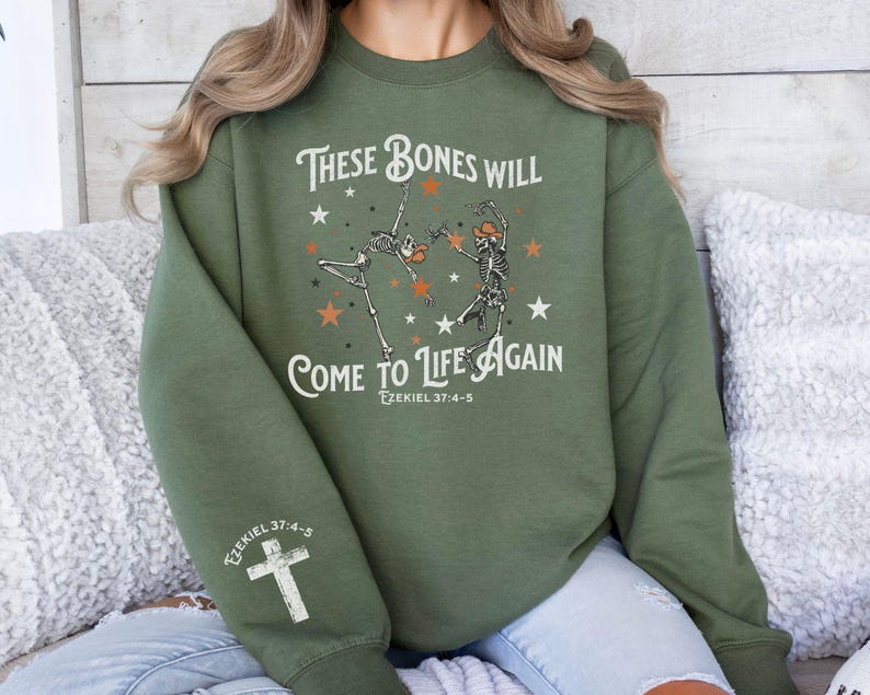 May include: Green sweatshirt with a graphic of two skeletons dancing with stars and the text "These bones will come to life again Ezekiel 37:4-5".