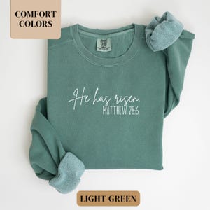 May include: Light green sweatshirt with the text "He has risen. Matthew 28:6" in white.