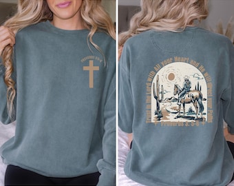 May include: A blue sweatshirt with a cross on the front and a cowboy riding a horse with the text "Trust in the Lord with All your Heart and He will direct your Paths" and "Proverbs 3:5-6" on the back.