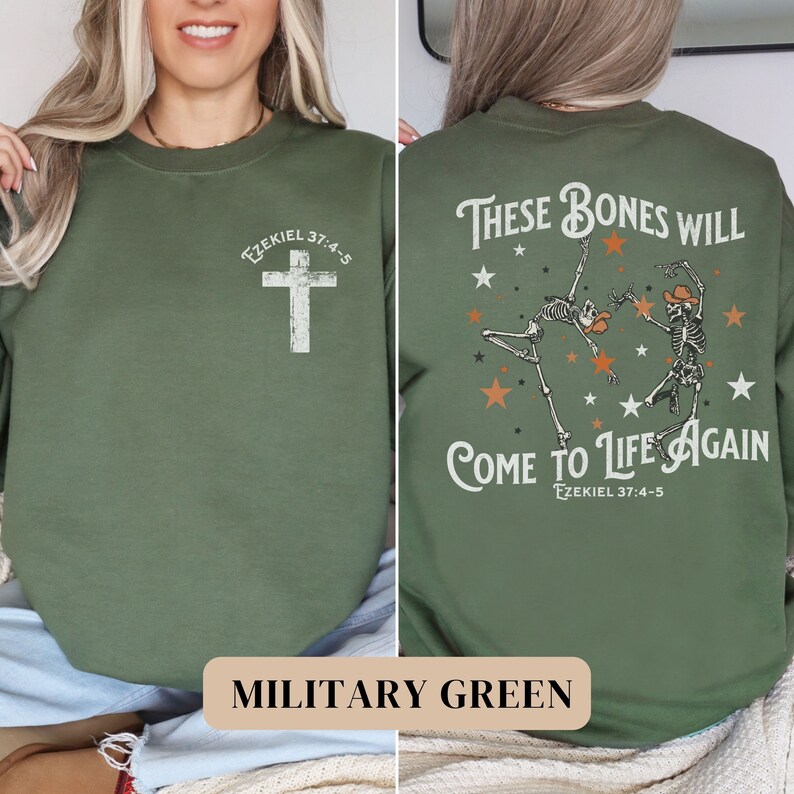 May include: A military green sweatshirt with a cross on the front and a graphic of two skeletons dancing with the text "These bones will come to life again" and "Ezekiel 37:4-5" on the back.
