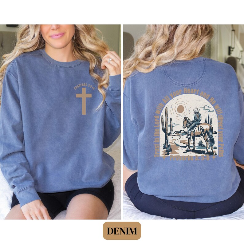 May include: A blue denim sweatshirt with a cross graphic on the front and a quote from Proverbs 3:5-6 on the back. The quote reads "Trust in the Lord with all your heart and he will make your paths straight."