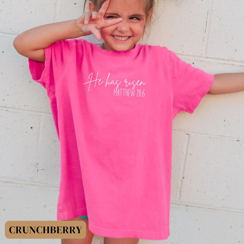 May include: A pink t-shirt with the text "He has risen Matthew 28:6" in white.