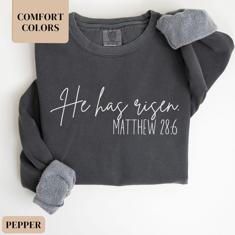 May include: A dark gray sweatshirt with the text "He has risen. Matthew 28:6" printed in white.