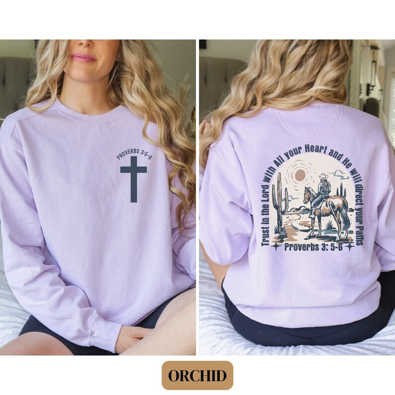 May include: A lavender sweatshirt with a cross and the text "Proverbs 3:5-6" on the front. The back of the sweatshirt features a cowboy riding a horse in a desert landscape with the text "Trust in the Lord with All your Heart and He will direct your Paths" and "Proverbs 3:5-6".