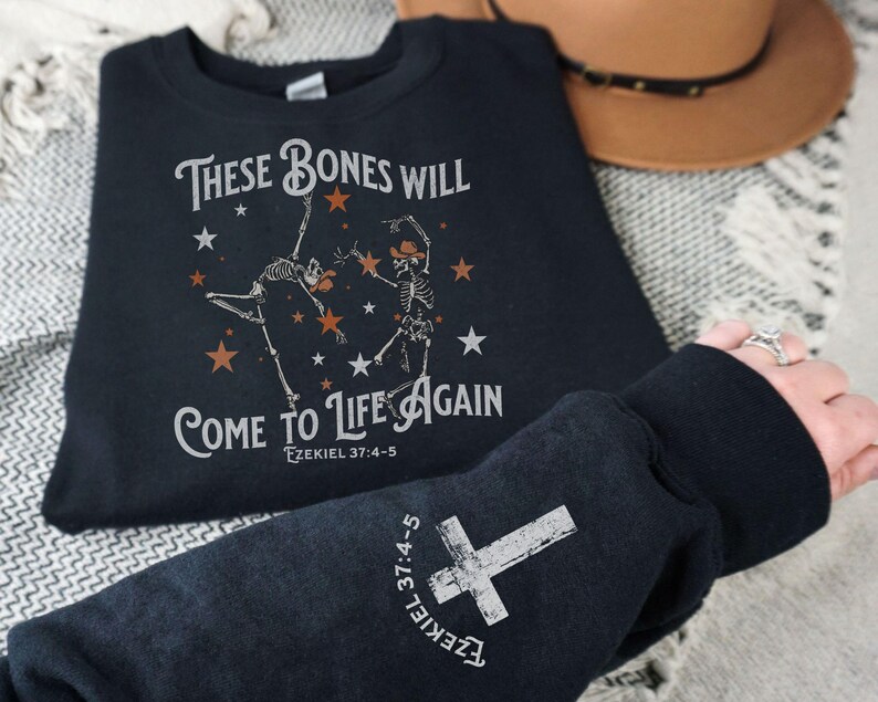 May include: Black sweatshirt with a white graphic print of two skeletons dancing with stars and the text "These bones will come to life again Ezekiel 37:4-5".