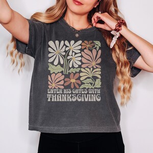 May include: A dark gray t-shirt with a vintage floral design and the text "Enter His Gates With Thanksgiving".