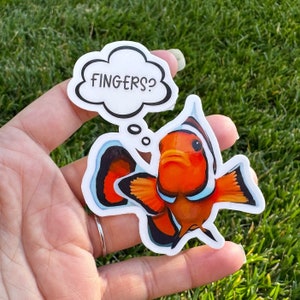 Può includere: Un adesivo di cartone animato di un pesce pagliaccio arancione e bianco con un fumetto sopra che dice "FINGERS?"