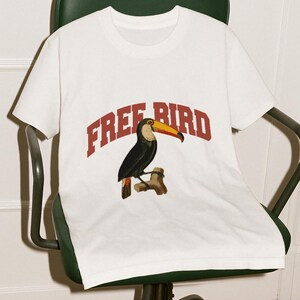 May include: White t-shirt with a toucan graphic and the text "FREE BIRD" in red.