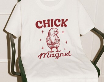 May include: White t-shirt with a red graphic of a chick and the text "Chick Magnet".
