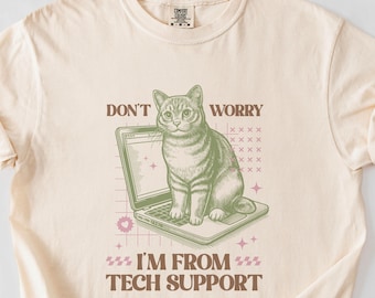May include: A beige t-shirt with a green cat sitting on a laptop. The text on the shirt reads "Don't Worry I'm From Tech Support".