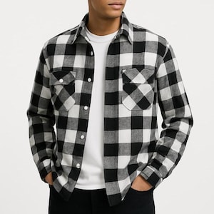 May include: A black and white checkered flannel shirt with two chest pockets and a button-down front. The shirt is worn over a white crew neck t-shirt. The sleeves are long and buttoned at the cuffs.