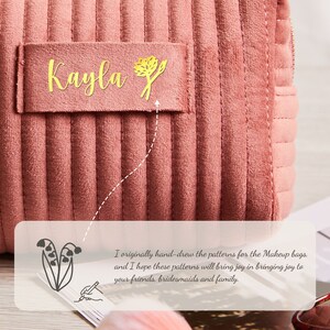 May include: A pink quilted makeup bag with a gold label that says "Kayla" and a small gold flower design. The bag is made of soft, plush fabric and has a zipper closure.