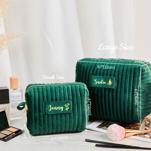 May include: Two green quilted velvet zippered makeup bags with gold zippers. The smaller bag is 17 cm by 12 cm and says "Jenny" on it. The larger bag is 22 cm by 15 cm and says "Sadie" on it.