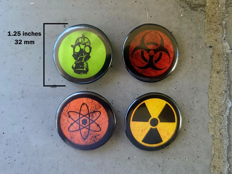 Four circular hazard warning button pins with distressed textures. gas mask silhouette on green. biohazard symbol on red. atom symbol on orange. radiation symbol on yellow. These represent various scientific and safety warning symbols commonly used to indicate dangerous materials or environments. Pins are 1.25" or 32mm round.  Metal Backing. Handmade in the USA. Not safe for children due to the sharp pin on the back. Brought to you by Brain Shudder Studio.