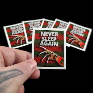 May include: A set of six square stickers with a red and green striped background. The stickers feature a white glove with a razor-sharp claw and the text "NEVER SLEEP AGAIN".