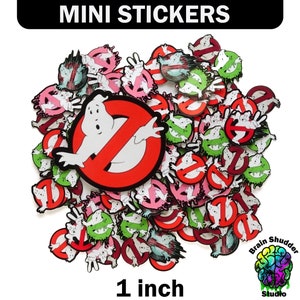 May include: A large pile of 1-inch Ghostbusters themed stickers. The stickers feature the Ghostbusters logo, the Stay Puft Marshmallow Man, and other Ghostbusters characters. The stickers are printed on white paper and have a glossy finish.